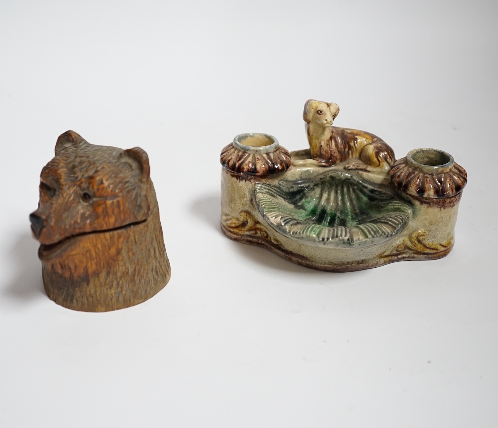 A Black Forest carved bear inkwell and a majolica inkwell surmounted with a dog, largest 14cm wide
